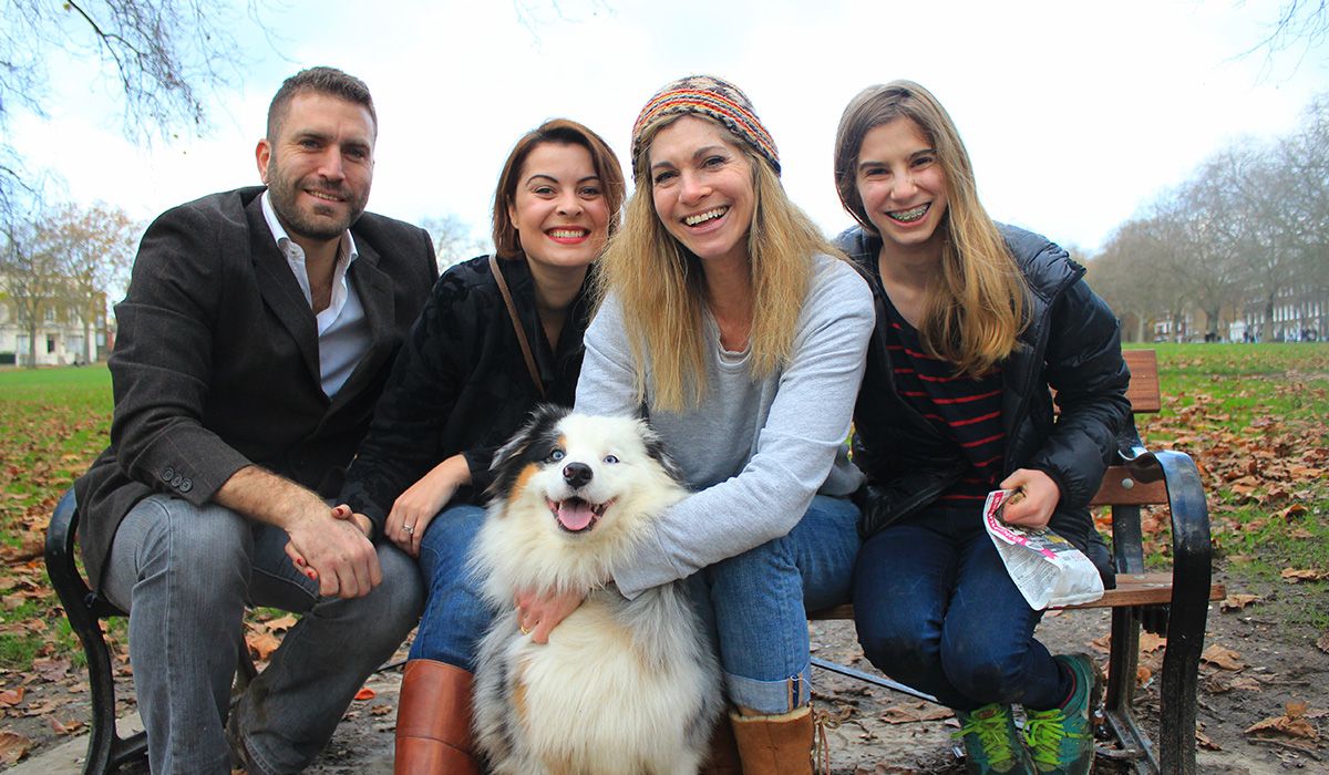 Four happy people on a park bench. With a very fluffy, mostly white, smiling dog